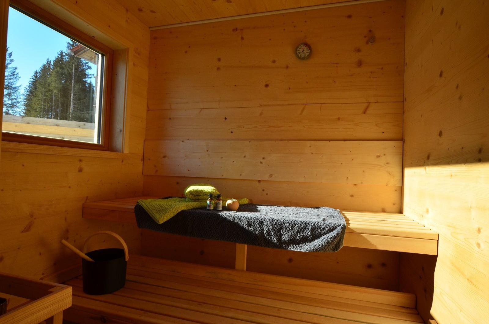 Sauna mit Holzbank, Fenster und Badematten.