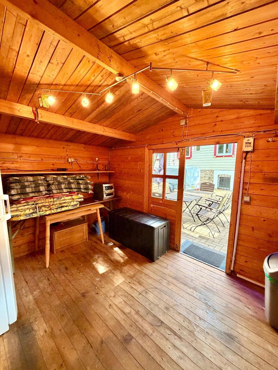 Holzvertäfelte Hütte mit Tisch, Stühlen und Blick auf Terrasse.