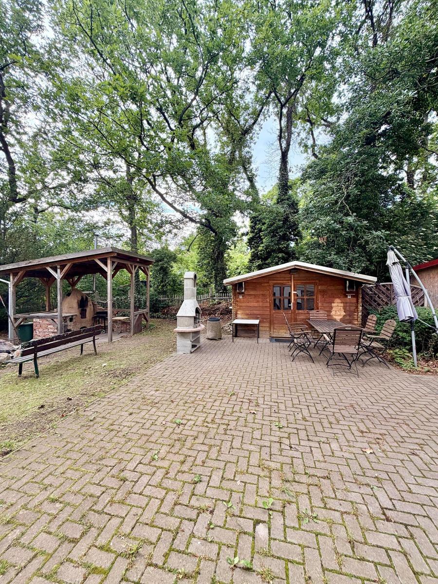 Holzhütte mit Sitzgelegenheiten und Grillbereich im Garten.