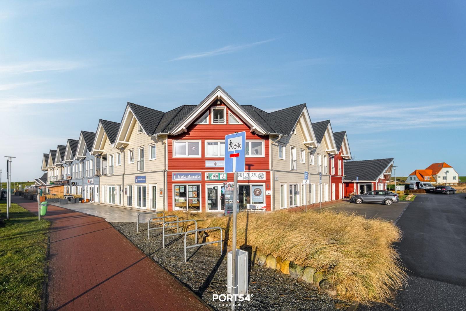Reihenhäuser mit Tourist-Info und Parkplatz an sonnigem Tag.
