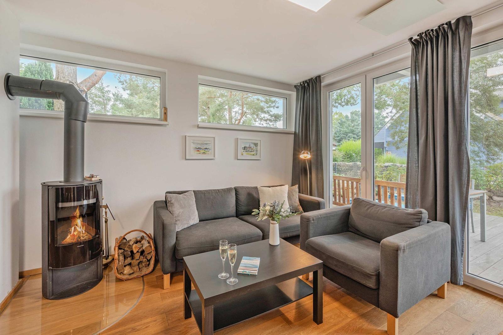 Wohnzimmer mit Sofa, Sessel, Kamin und Blick auf Balkon