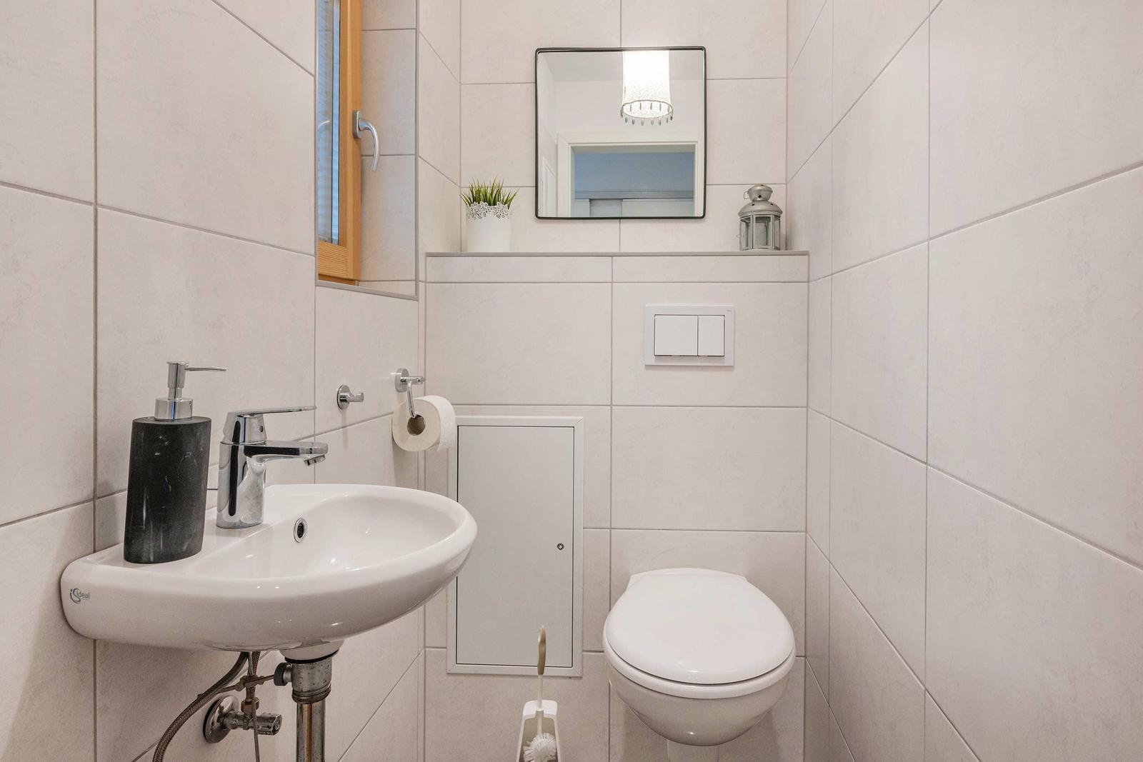 Badezimmer mit Waschbecken, Toilette und Spiegel an der Wand.