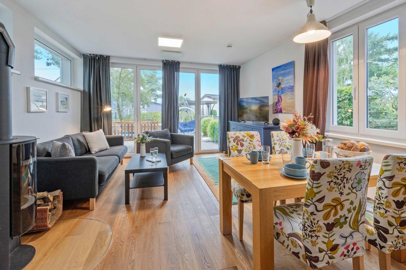 Wohn- und Essbereich mit Holzboden, Sofa, Esstisch und Blick auf Balkon.