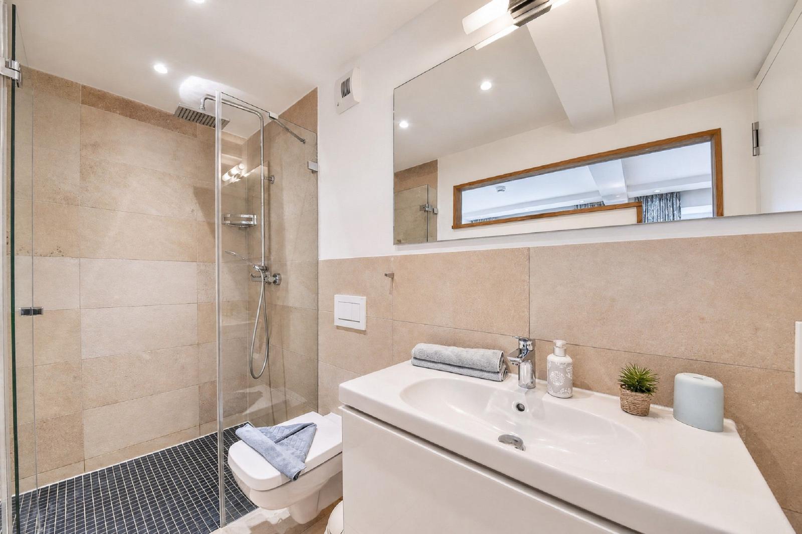 Badezimmer mit Dusche, Waschbecken und Spiegel