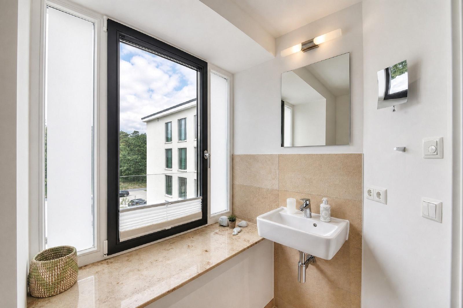 Badezimmer mit Waschbecken, Spiegel und großem Fenster mit Blick auf Gebäude.
