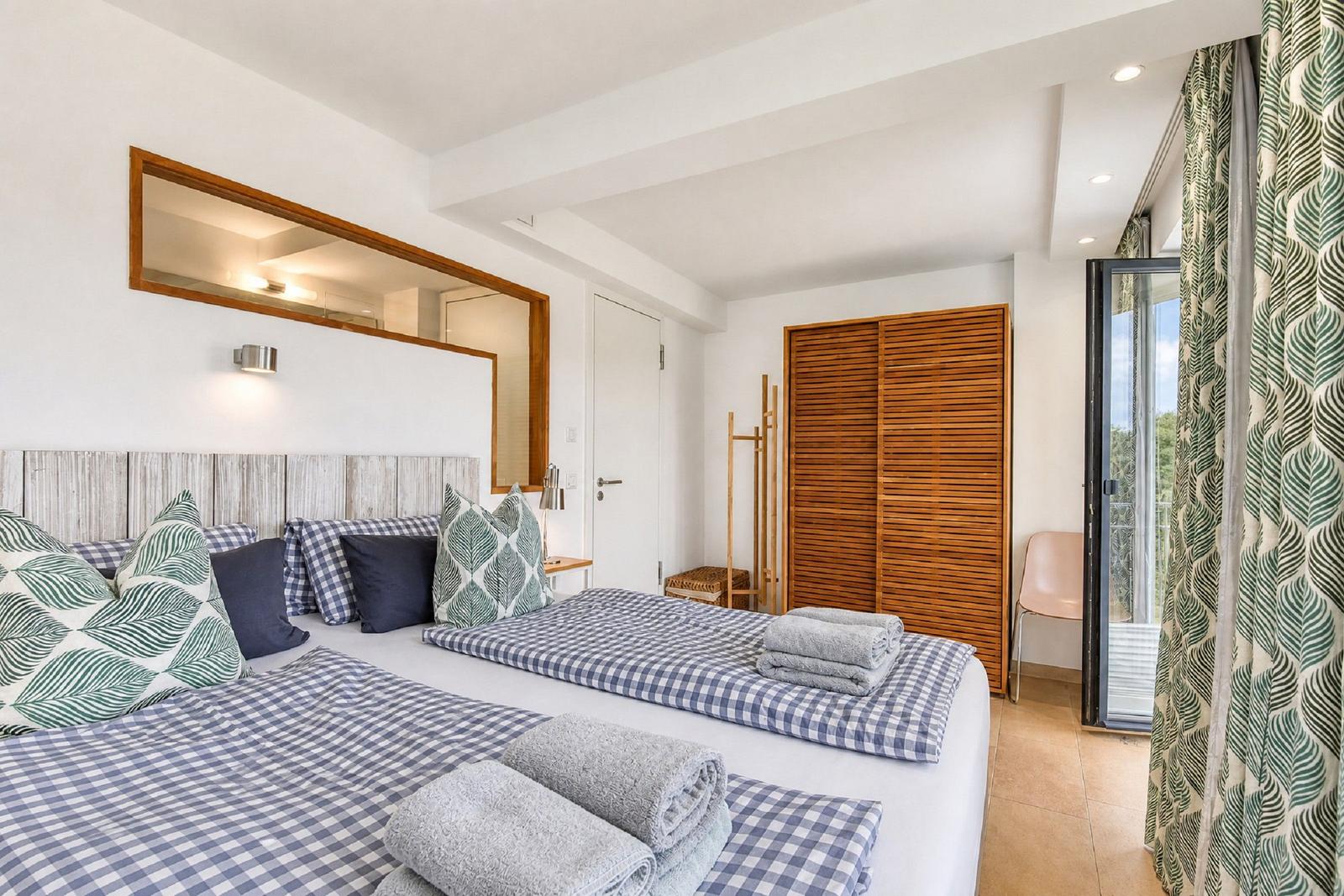 Schlafzimmer mit Doppelbett, Spiegelschrank und Balkontür.