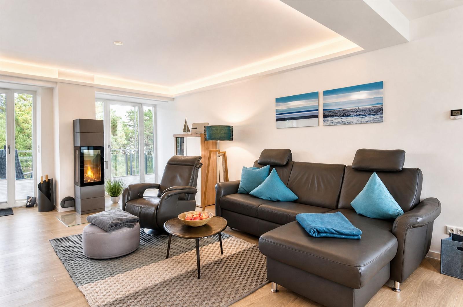 Wohnzimmer mit Ledersofa, Sessel, Kamin und Blick auf Balkon.