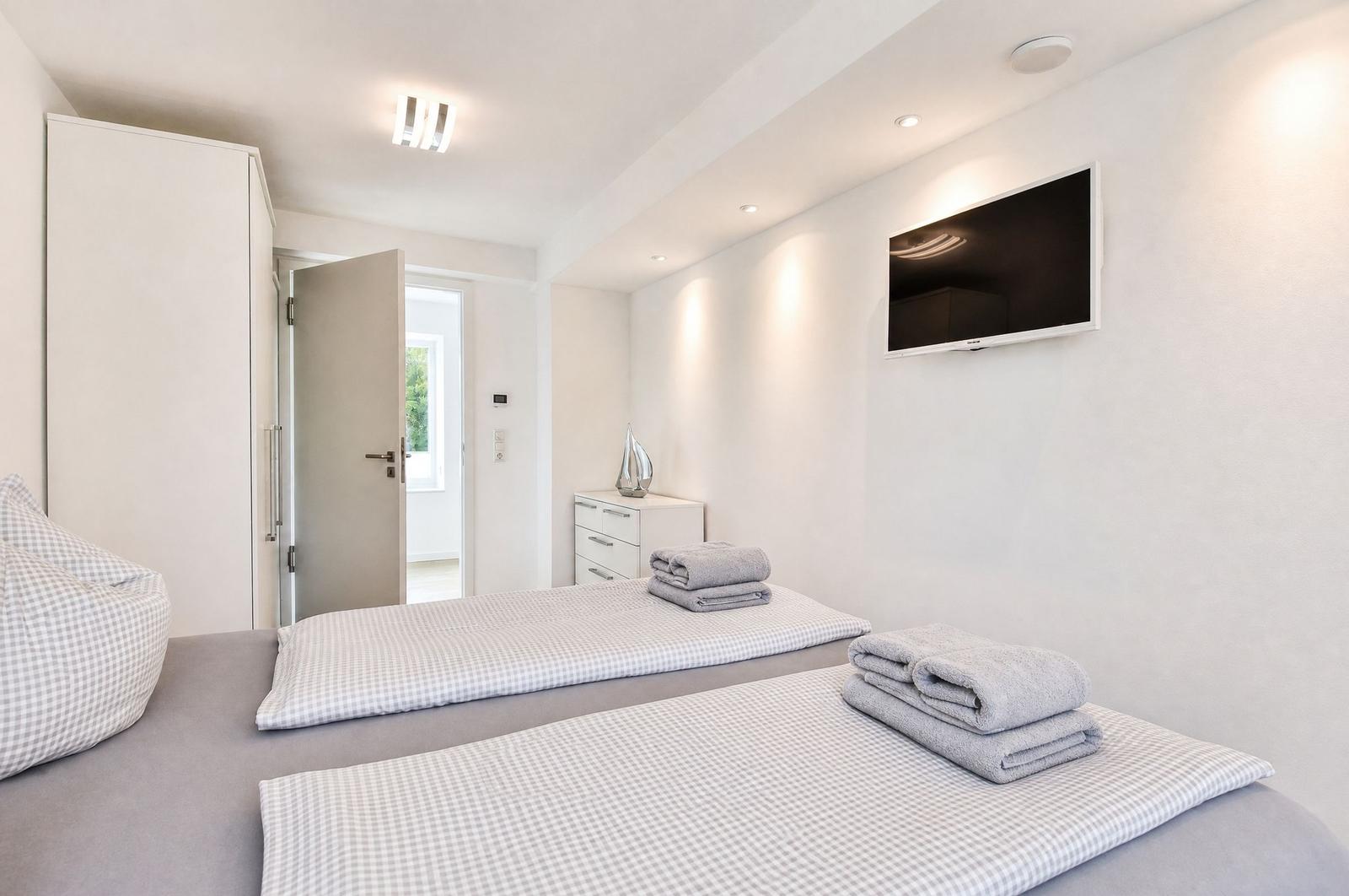 Schlafzimmer mit zwei Betten, Fernseher und Kleiderschrank.