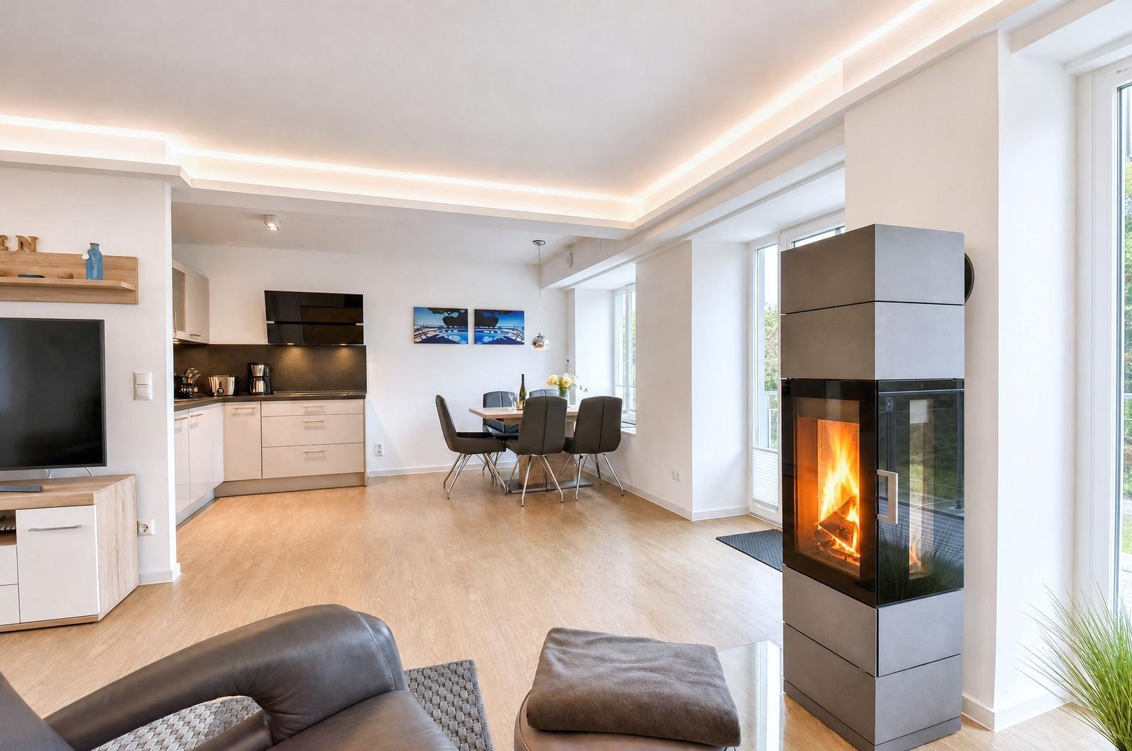 Wohnung mit moderner Küche, Essbereich und Kaminofen. Holzboden und große Fenster.