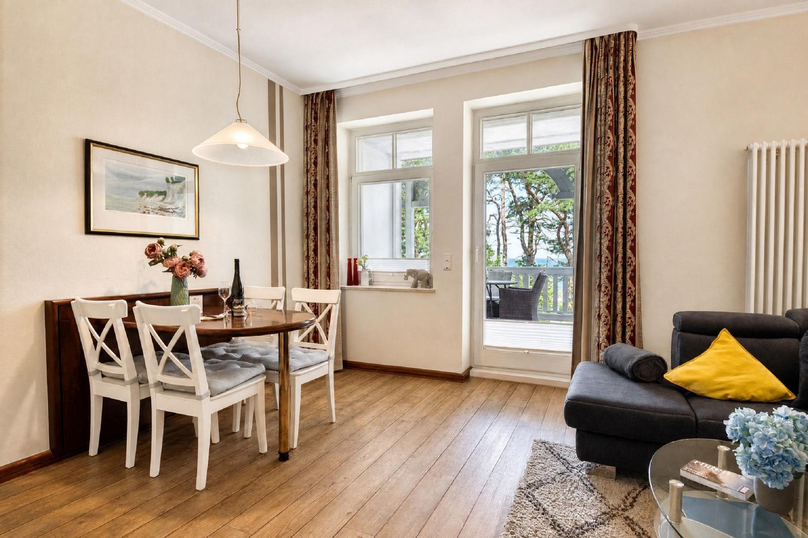 Essbereich mit Tisch und Stühlen, Wohnbereich mit Sofa und Blick auf Balkon.