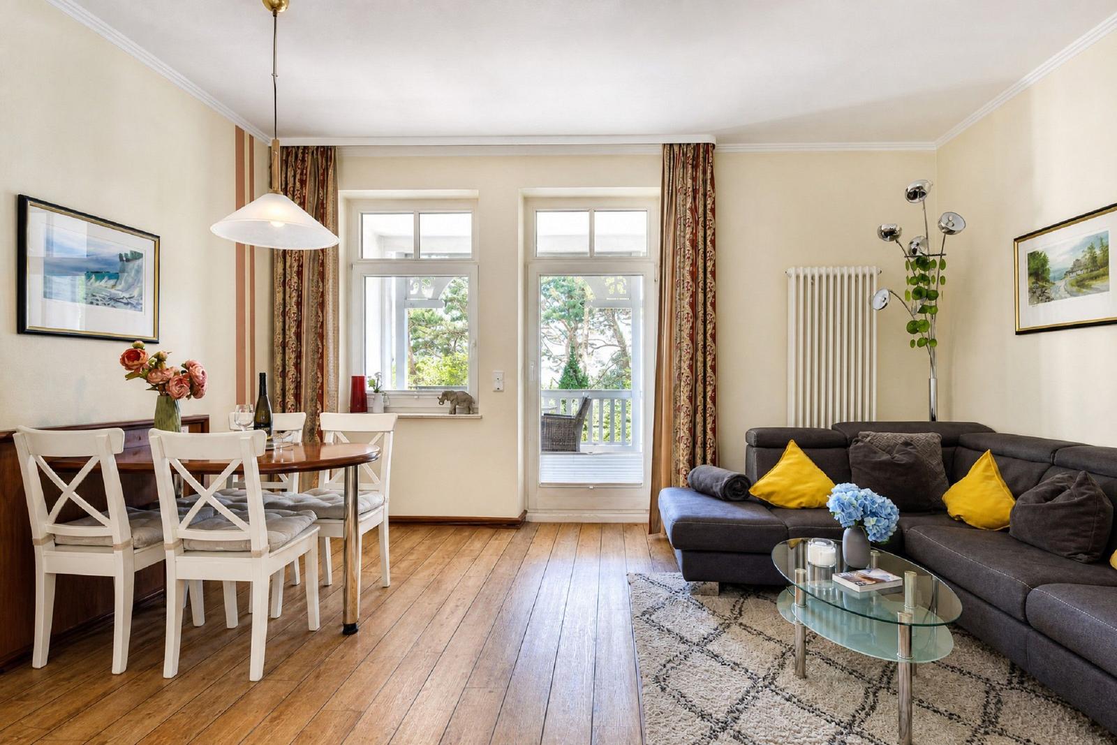 Wohn- und Essbereich mit Sofa, Tisch und Blick auf Balkon.
