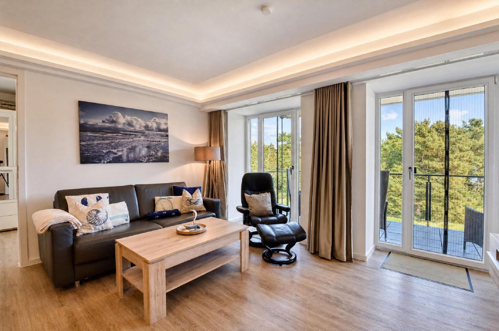Wohnzimmer mit Sofa, Sessel und Balkon. Blick auf Wald. Holzfußboden und Wandbild.
