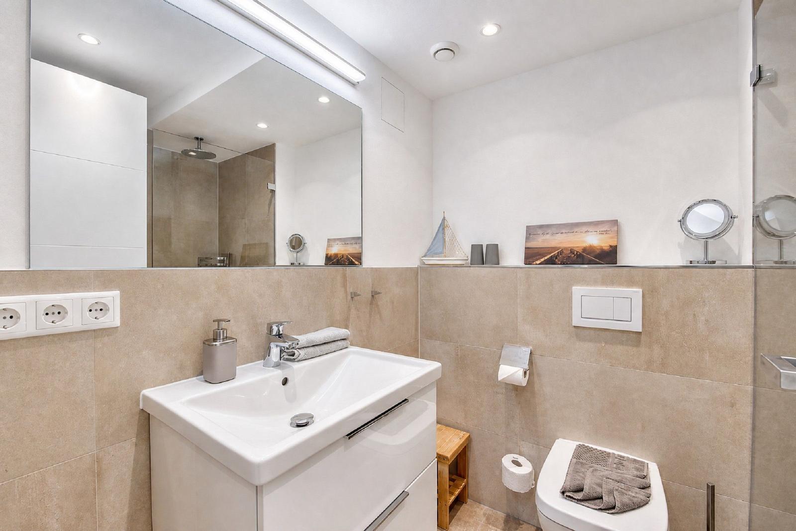 Badezimmer mit Waschbecken, Spiegel, Toilette und Dusche