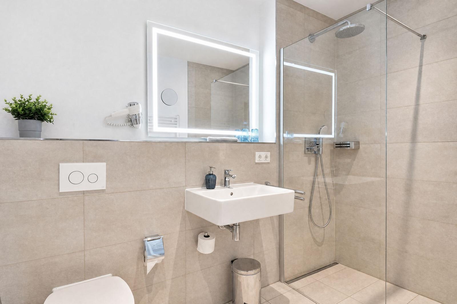 Badezimmer mit Dusche, Waschbecken und Spiegel