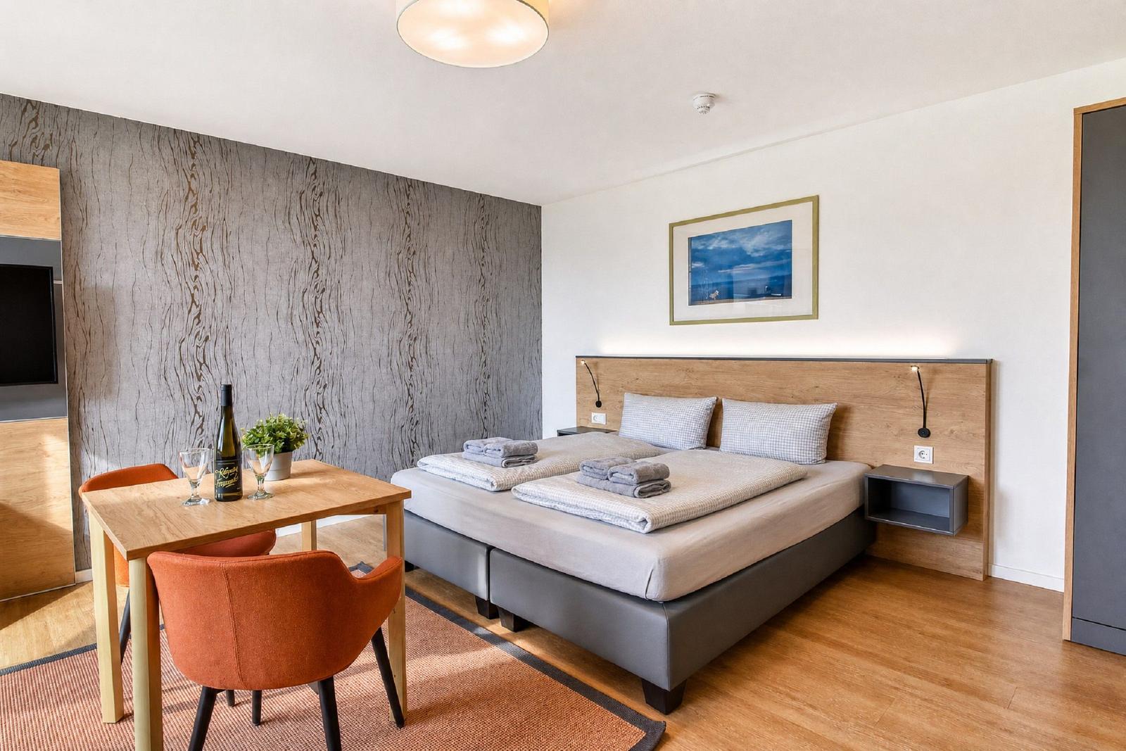Bedroom with bed, table and chairs. Wall with pattern. Picture on the wall.