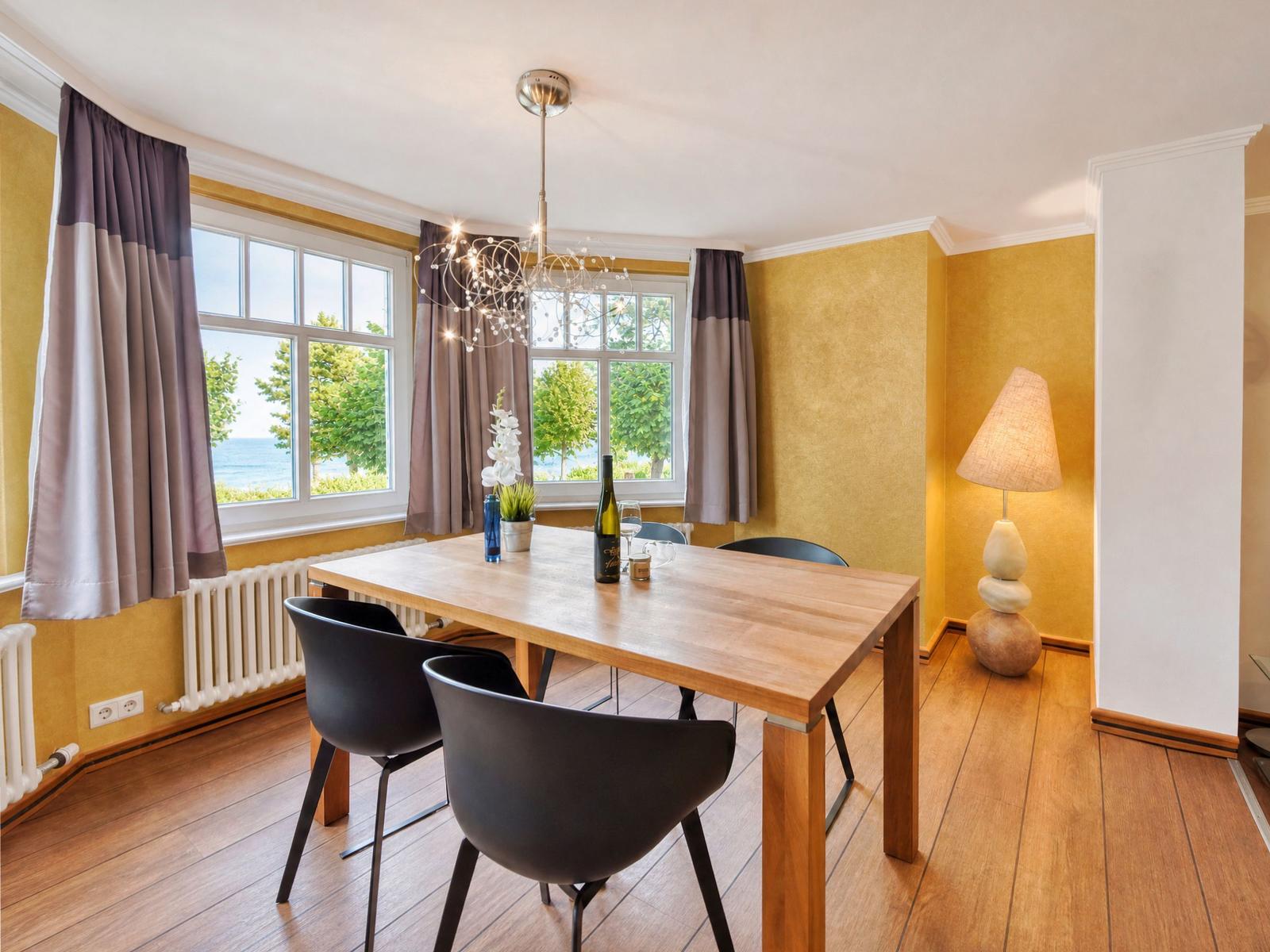 Esszimmer mit Holztisch, schwarzen Stühlen und Blick auf den See.