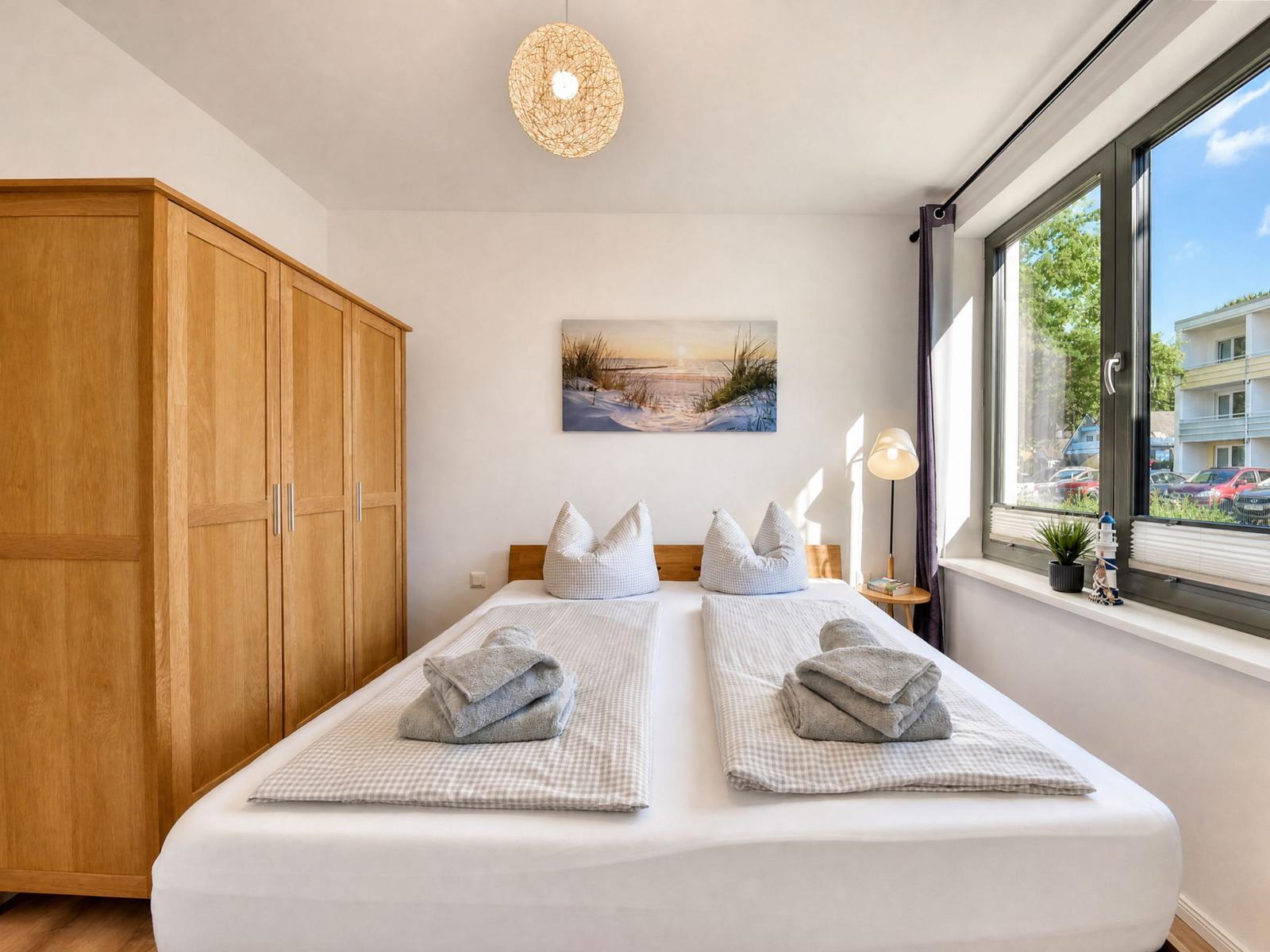 Bedroom with double bed, wooden wardrobe, and window view.