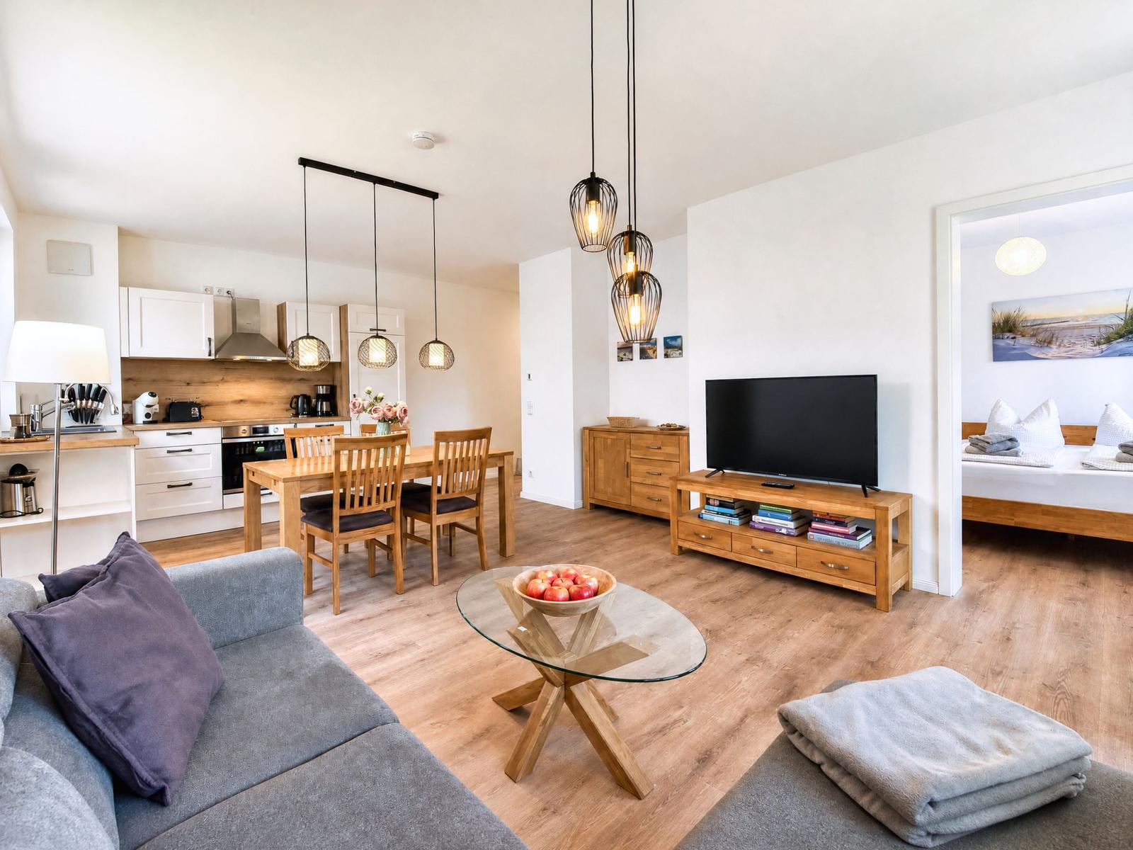 Apartment with kitchen, dining area, living room, and bedroom. Wooden furniture and TV.