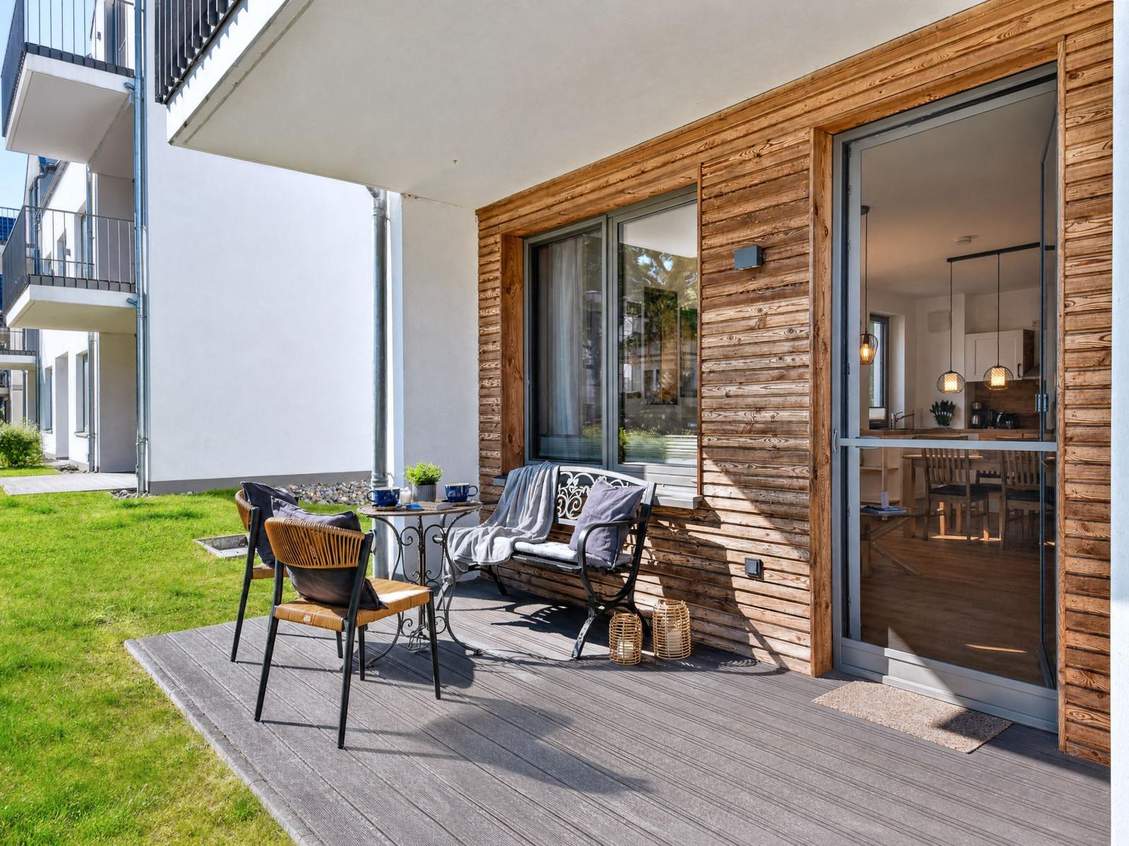 Terrace with table, chairs, and bench. Glass door leads into the interior.