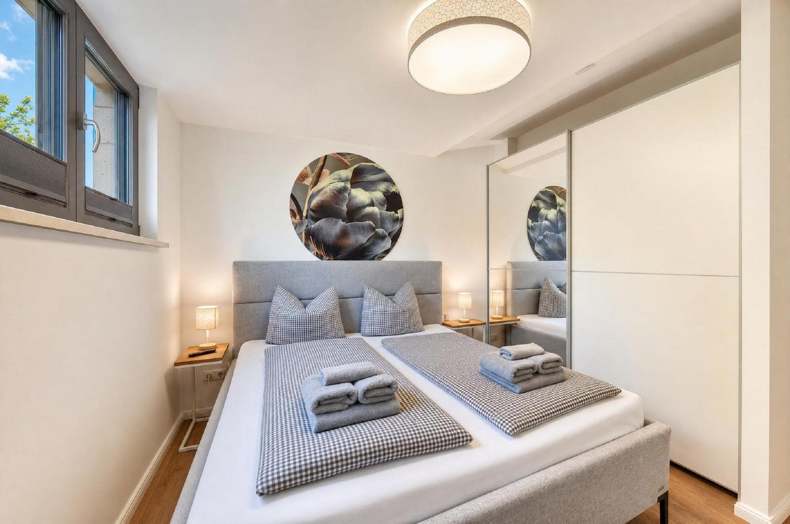Schlafzimmer mit Doppelbett, Wandbild und integriertem Schrank.