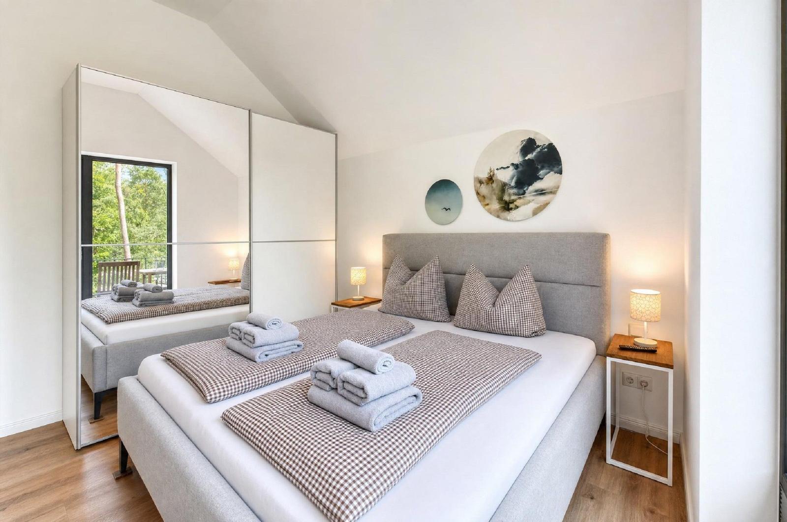 Schlafzimmer mit Doppelbett, Spiegelschrank und Wanddekoration.
