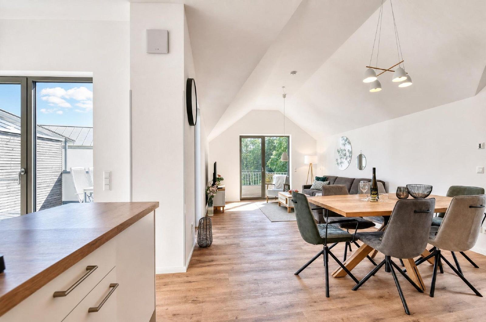 Wohn- und Essbereich mit Holzboden, Esszimmertisch und Schlafzimmer im Hintergrund.