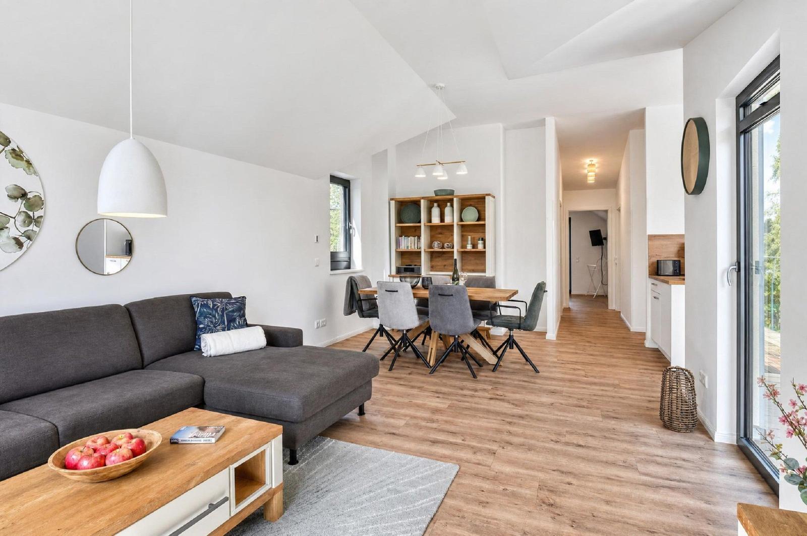Wohn- und Essbereich mit Holzboden, Sofa, Tisch und Stühlen.