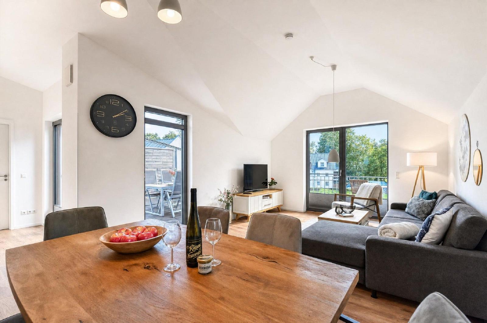 Ein Essbereich mit Holztisch, Sofa und TV. Durchgänge zu Terrasse und Garten.