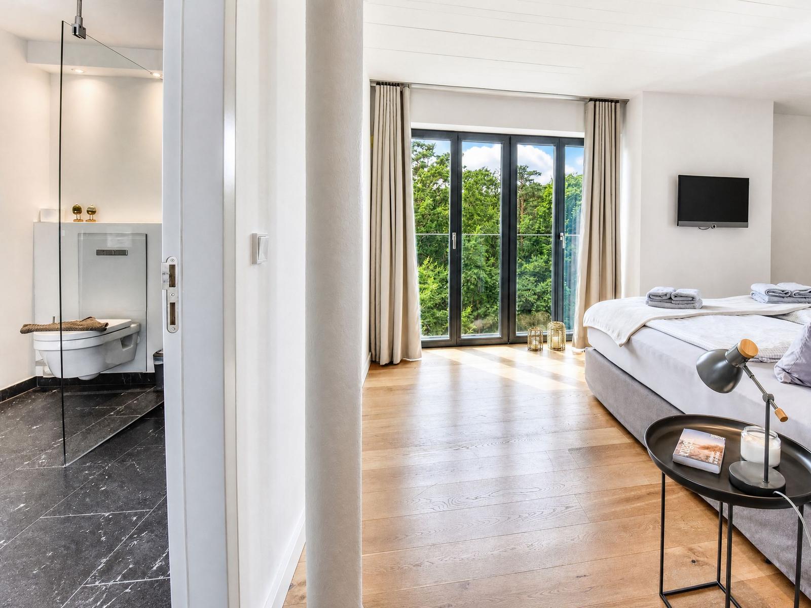 Schlafzimmer mit Blick auf Wald, Dusche und Bad mit Toilette