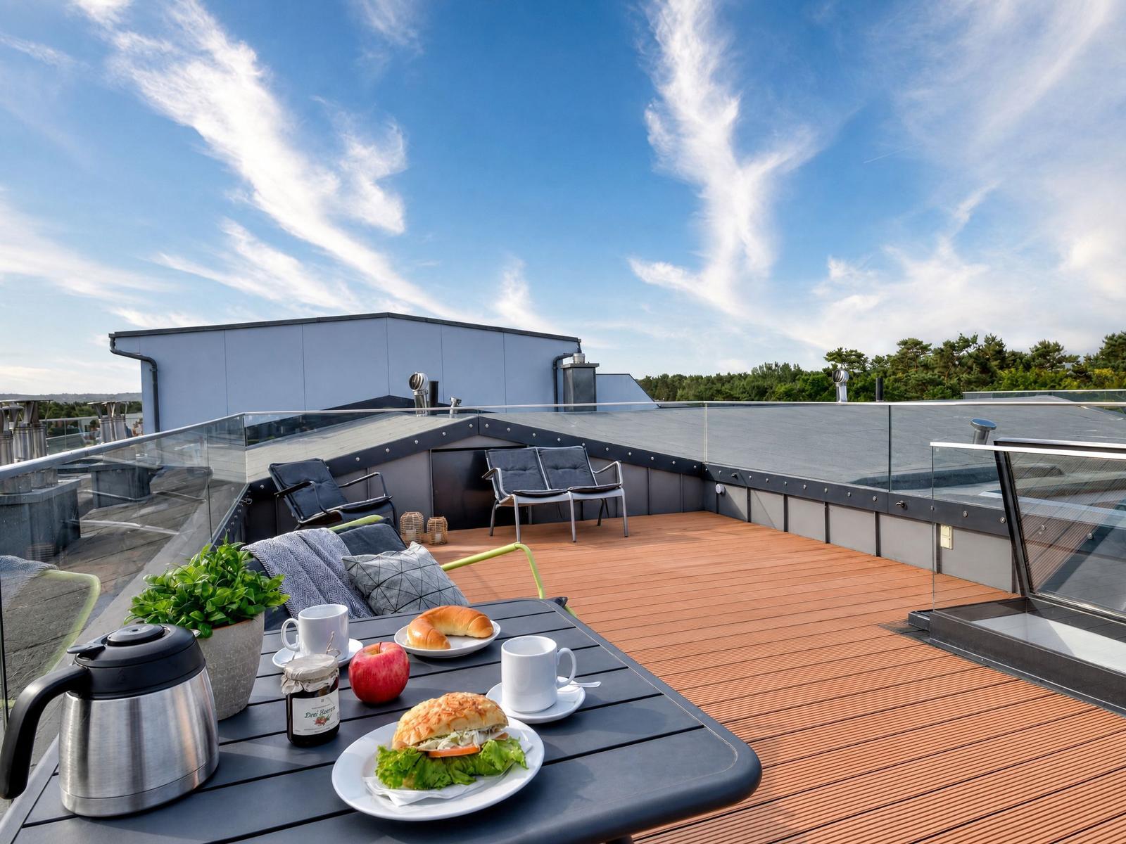 Rooftop-Terrasse mit Tisch, Stühlen und Blick auf den Himmel