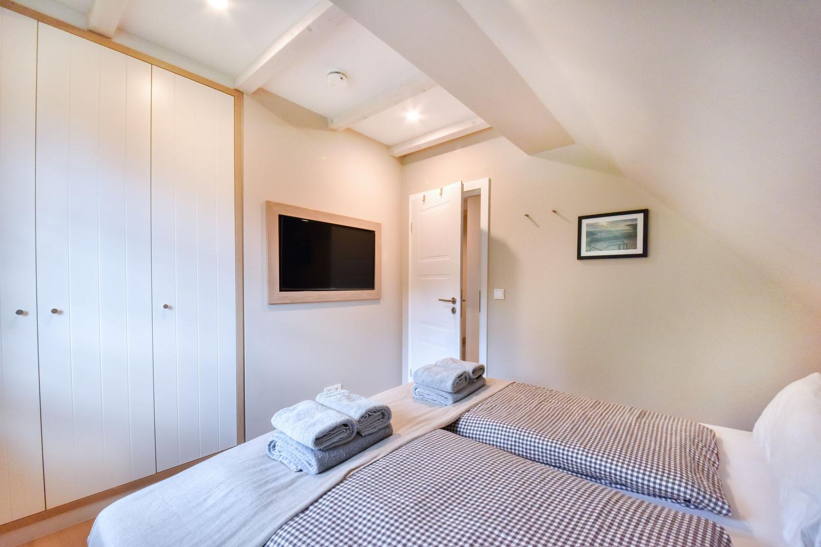 Schlafzimmer mit Doppelbett, Kleiderschrank und Fernseher an der Wand.