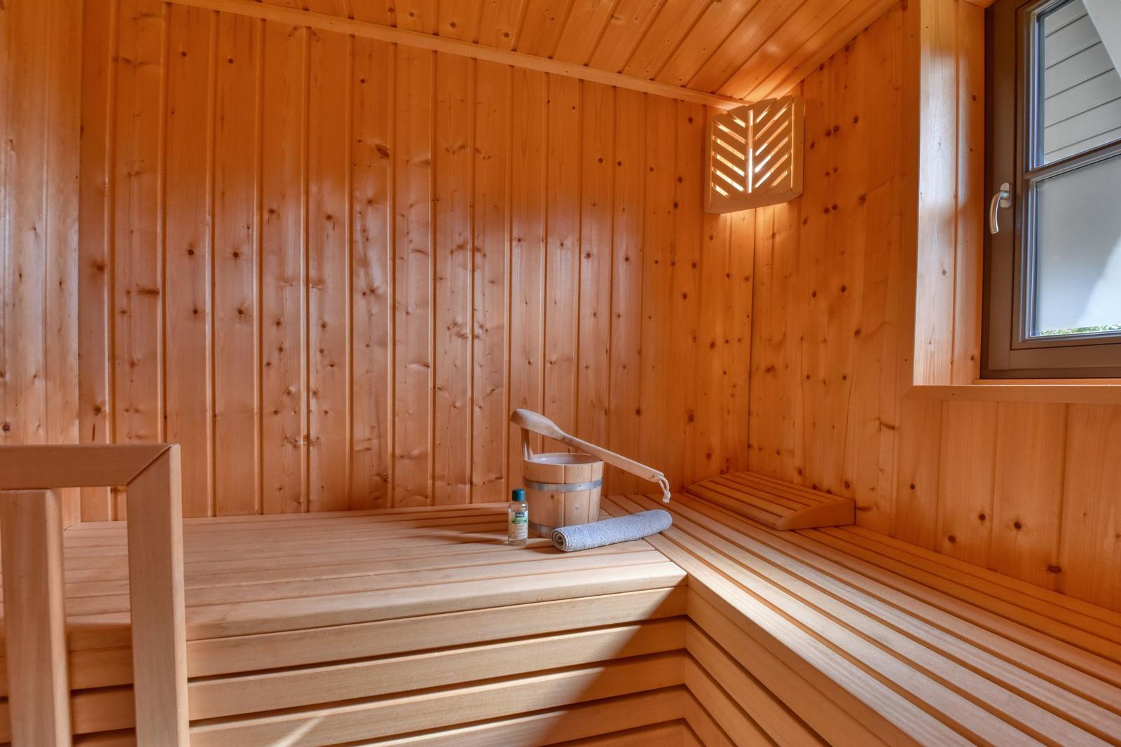 Holzsauna mit Sitzbänken, Eimer und Handtuch.