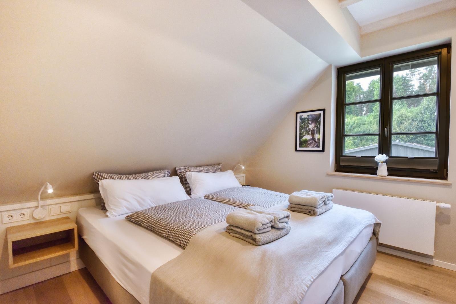 Schlafzimmer mit Doppelbett, Fenster und Holzboden