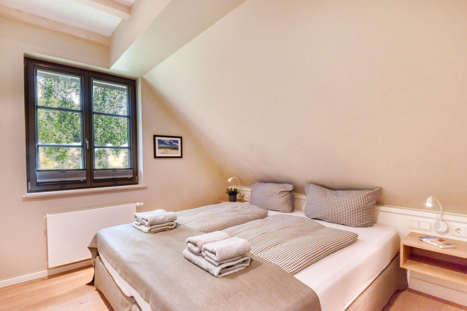 Schlafzimmer mit Doppelbett, Fenster und Nachttisch