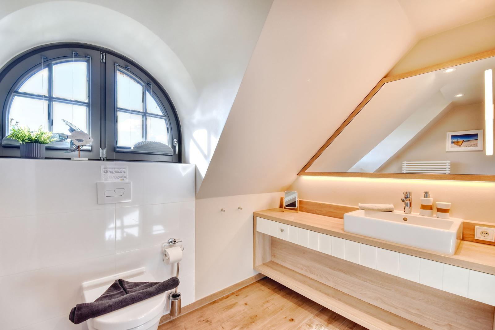 Badezimmer mit Holzregal, Waschtisch und Bogenfenster.