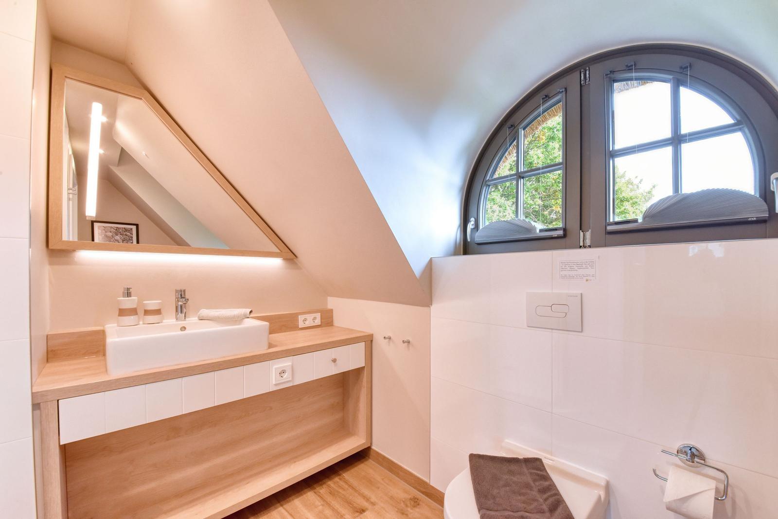 Badezimmer mit Waschbecken, Spiegel und Badezimmerfenster