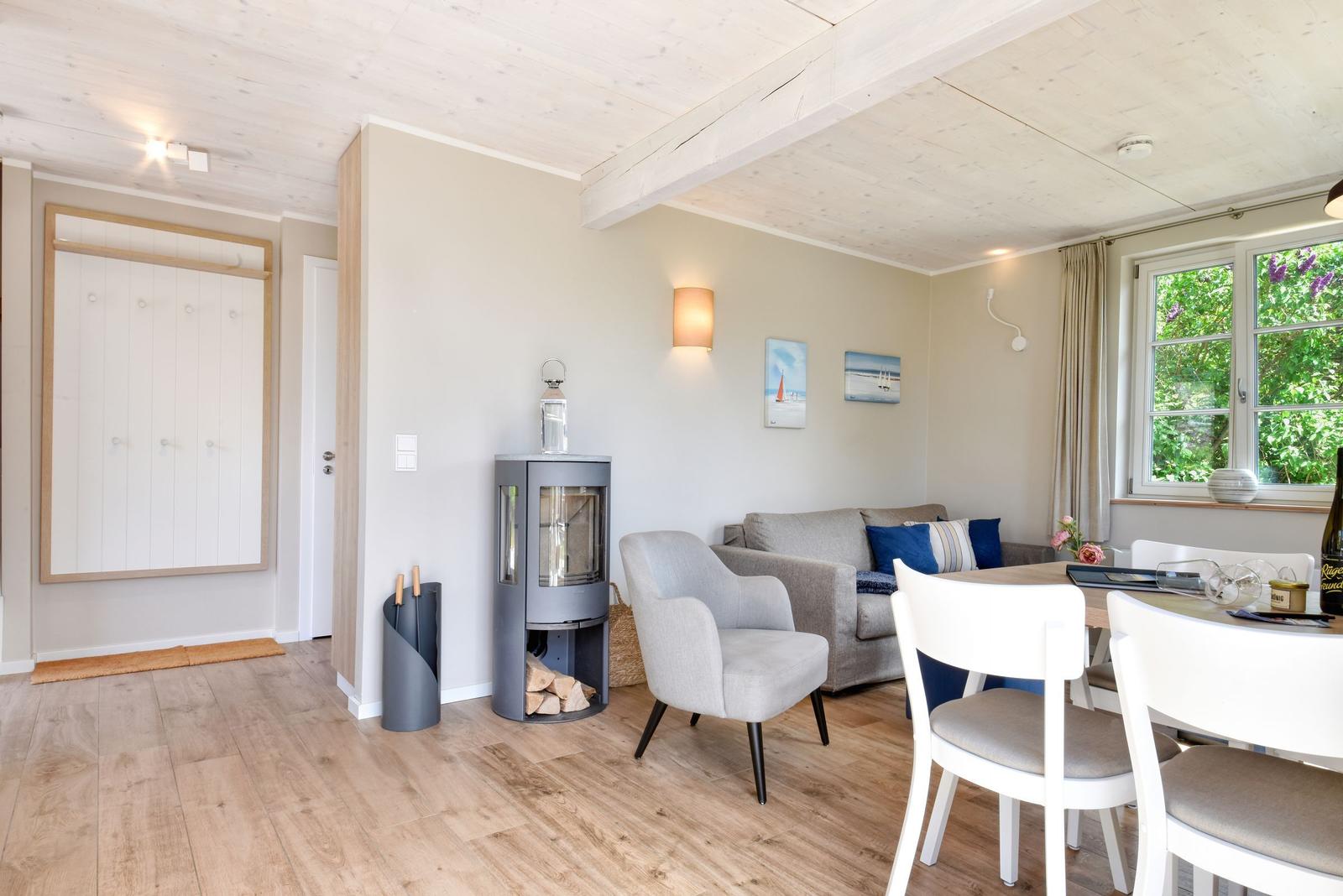 Wohn- und Essbereich mit Holzfußboden, Sofa, Stühlen und Kaminofen.