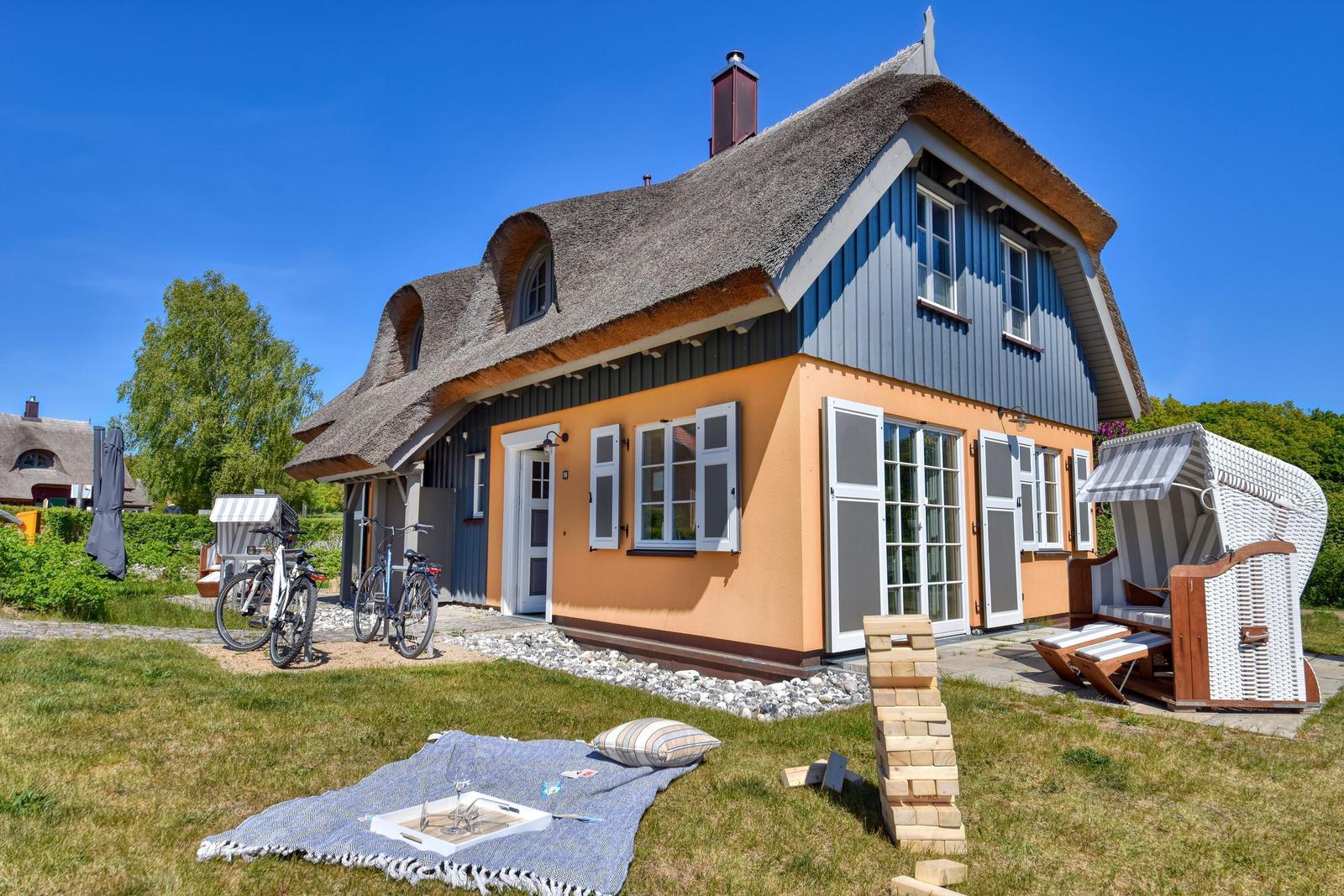 Haus mit Strohdach, Fahrräder und Strandkörbe im Garten.