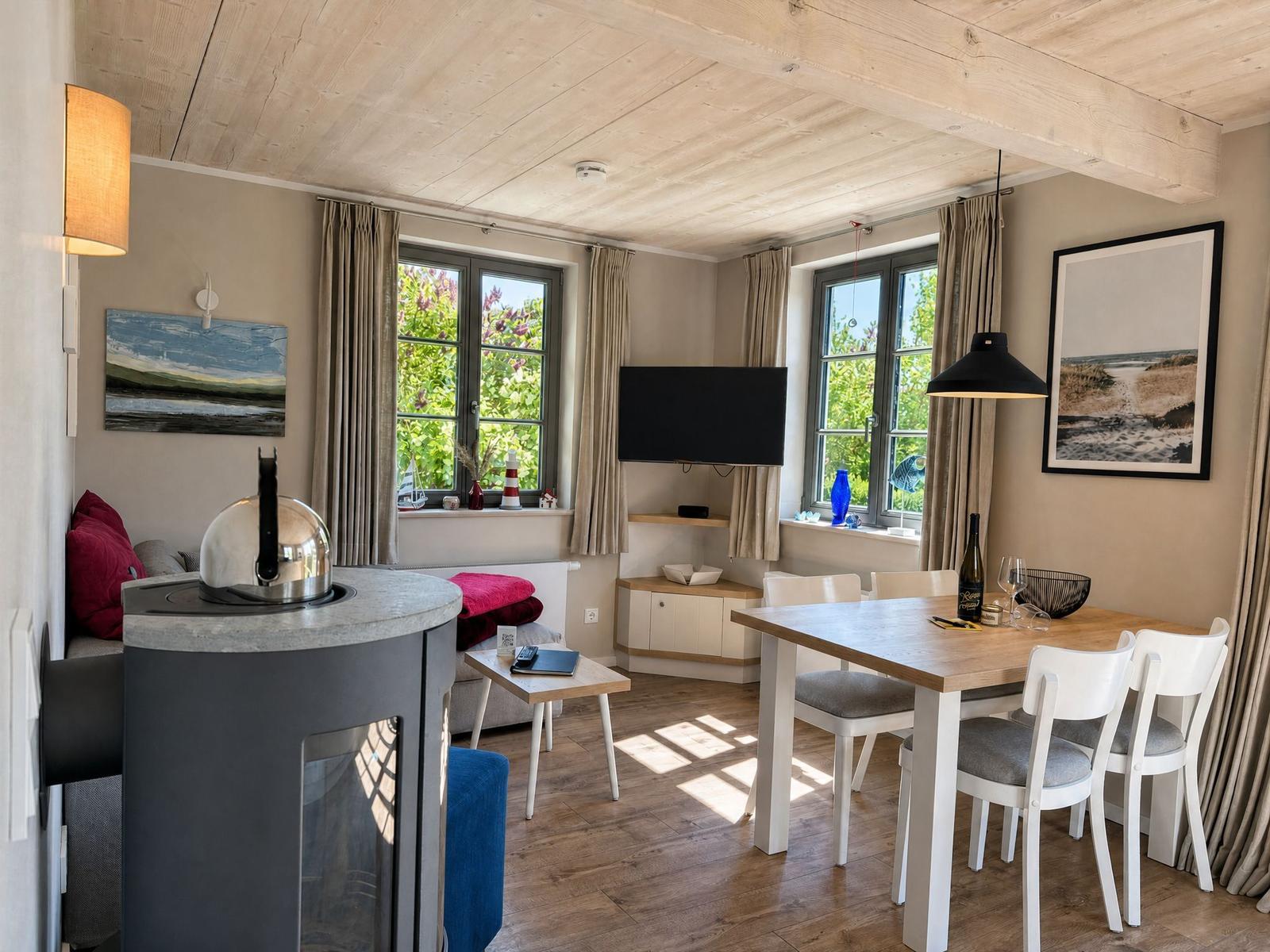 Living and dining area with wooden floor, TV, and table with chairs.