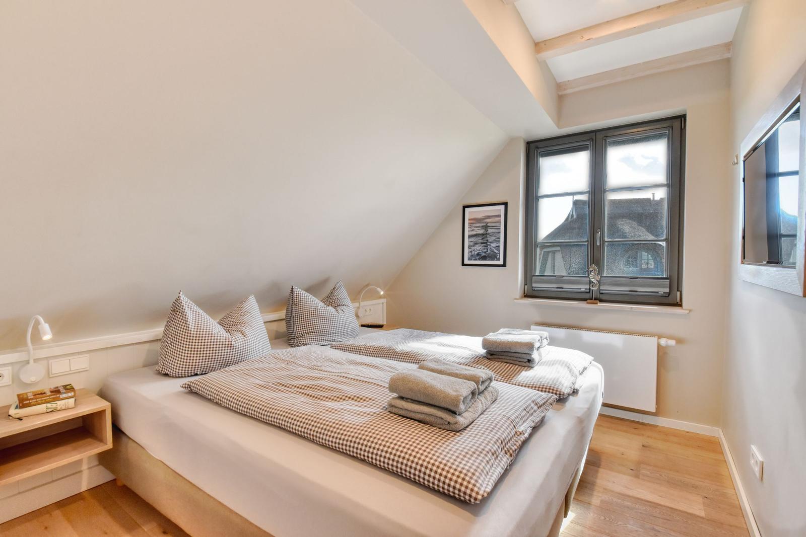 Bedroom with double bed, window, and wooden floor.