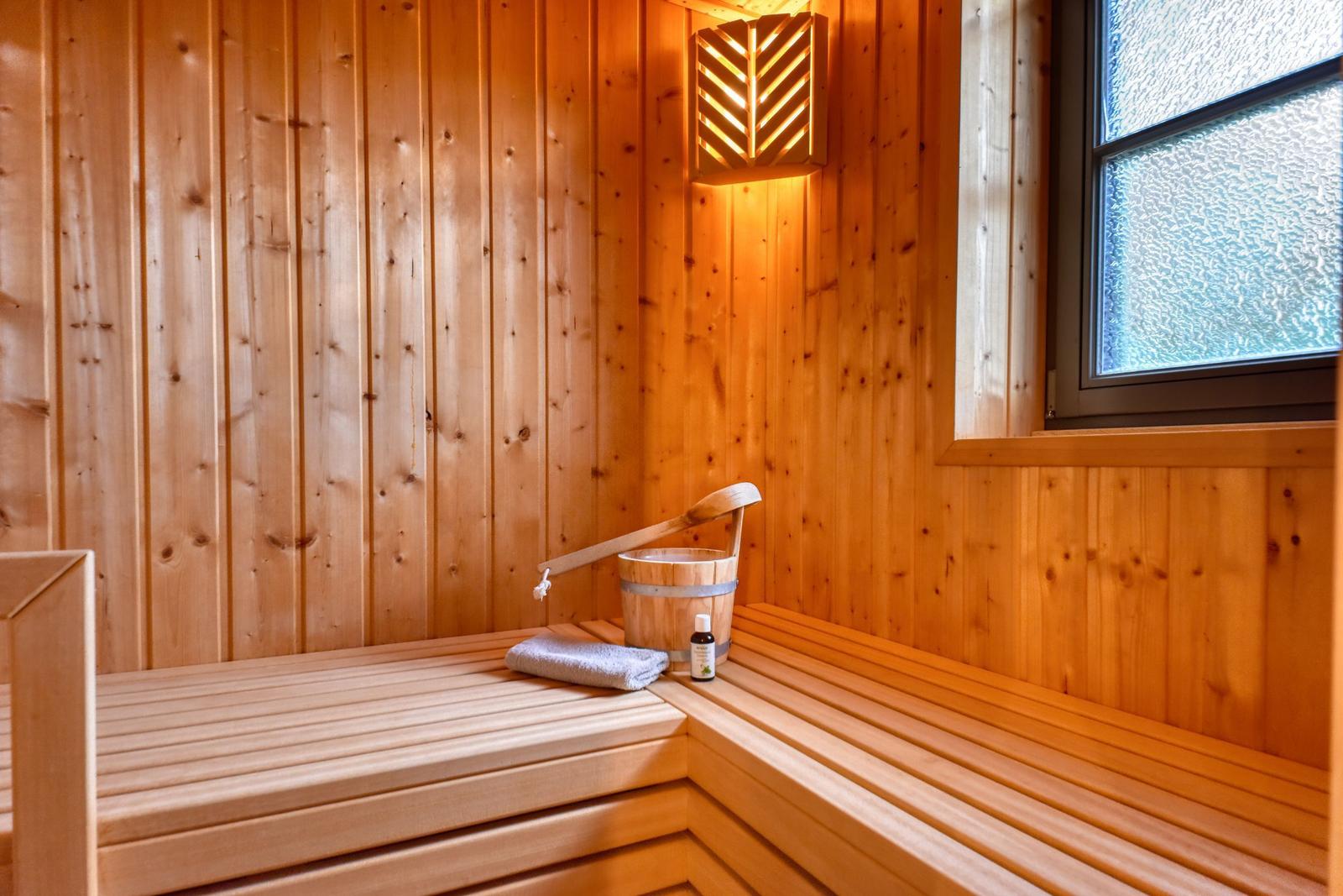 Sauna with wooden walls, bench, bucket, and window