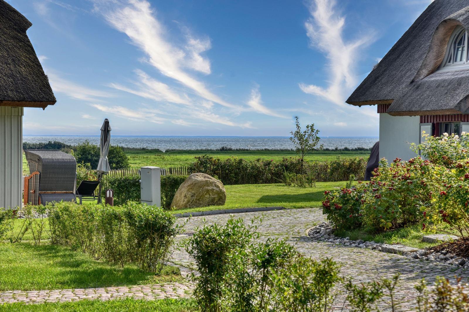 House with thatched roof, garden path, and sea view.