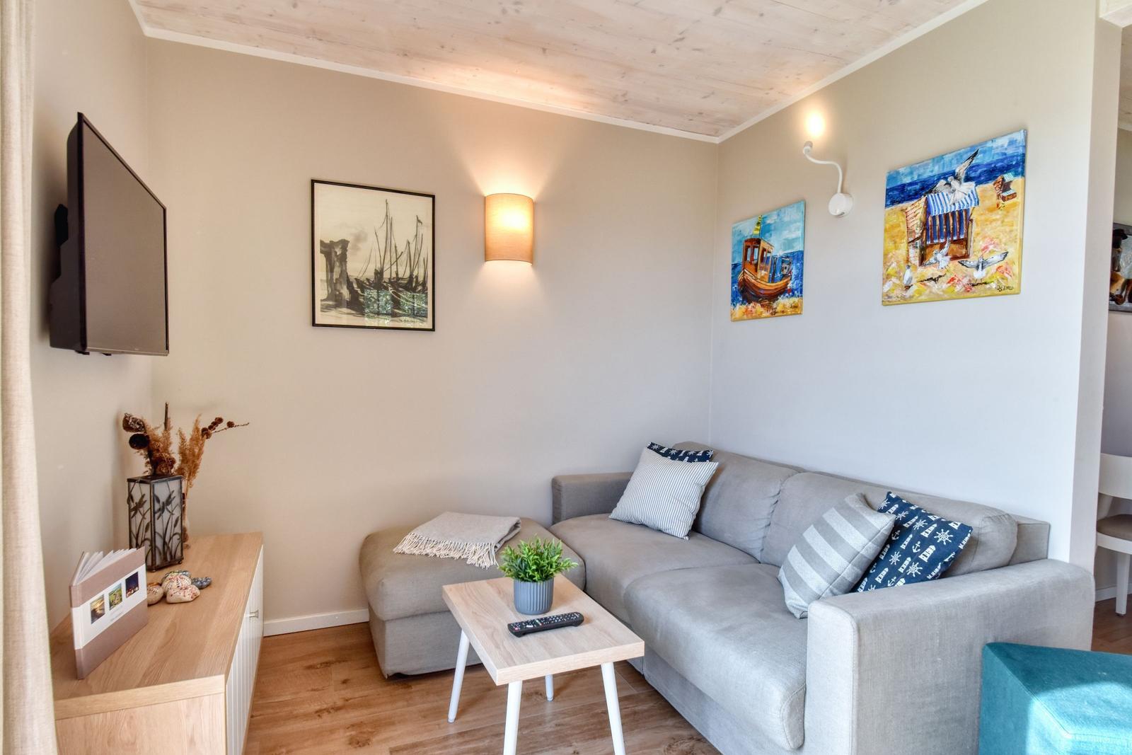 Wohnzimmer mit Sofa, Couchtisch und Wandbildern an den Wänden.