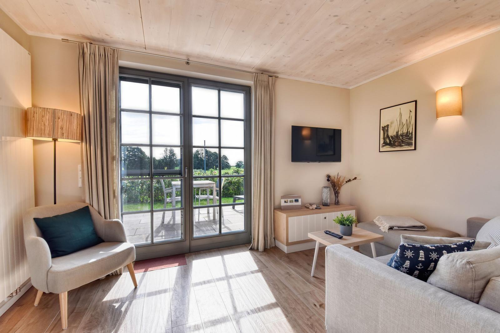 Wohnzimmer mit Balkon, Fernseher und Sofa. Holzdecke und helle Wände.