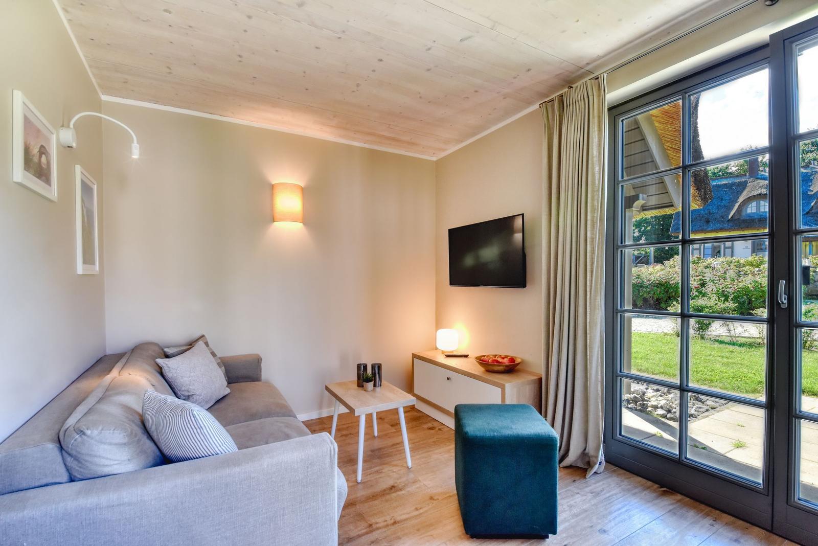 Living room with sofa, TV, and view of garden.