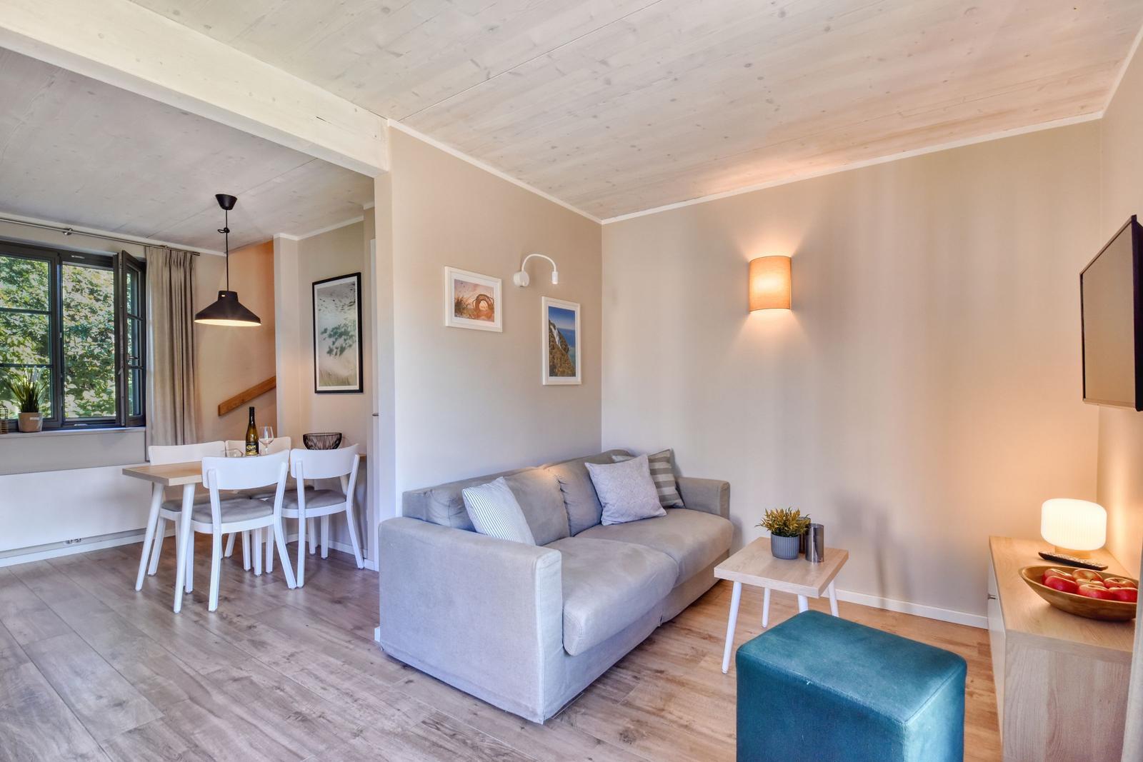 Living and dining area with sofa, table, chairs, and window view.