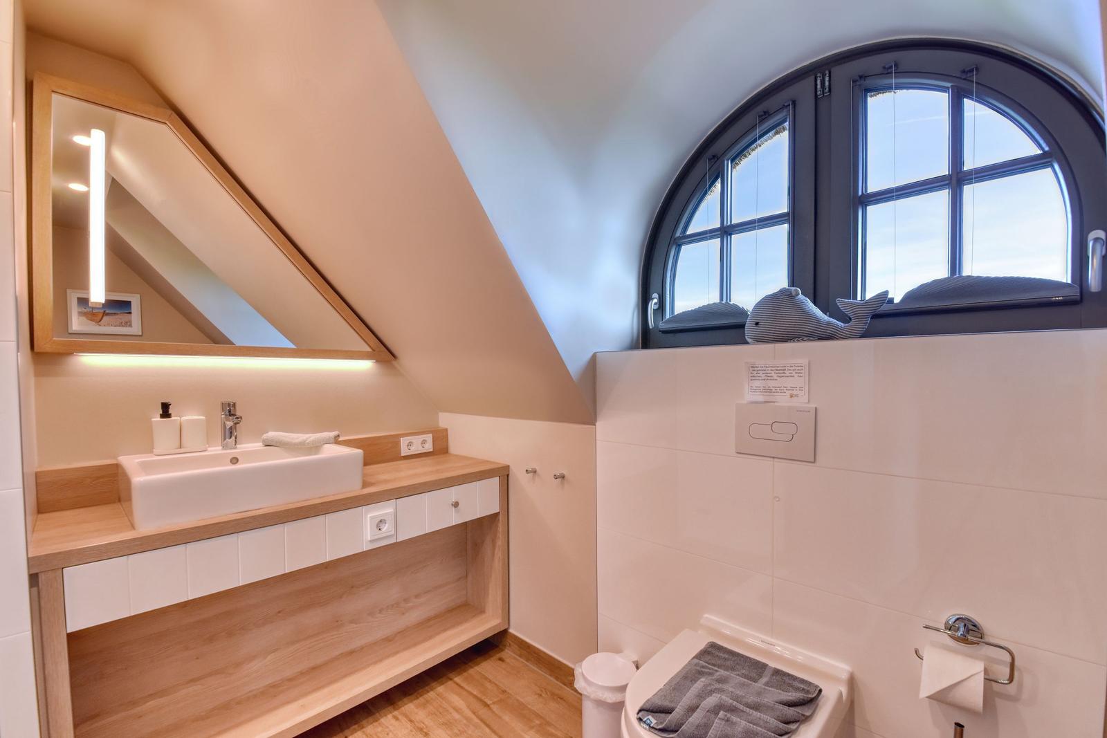 Badezimmer mit Waschbecken, Spiegel und großem Bogenfenster