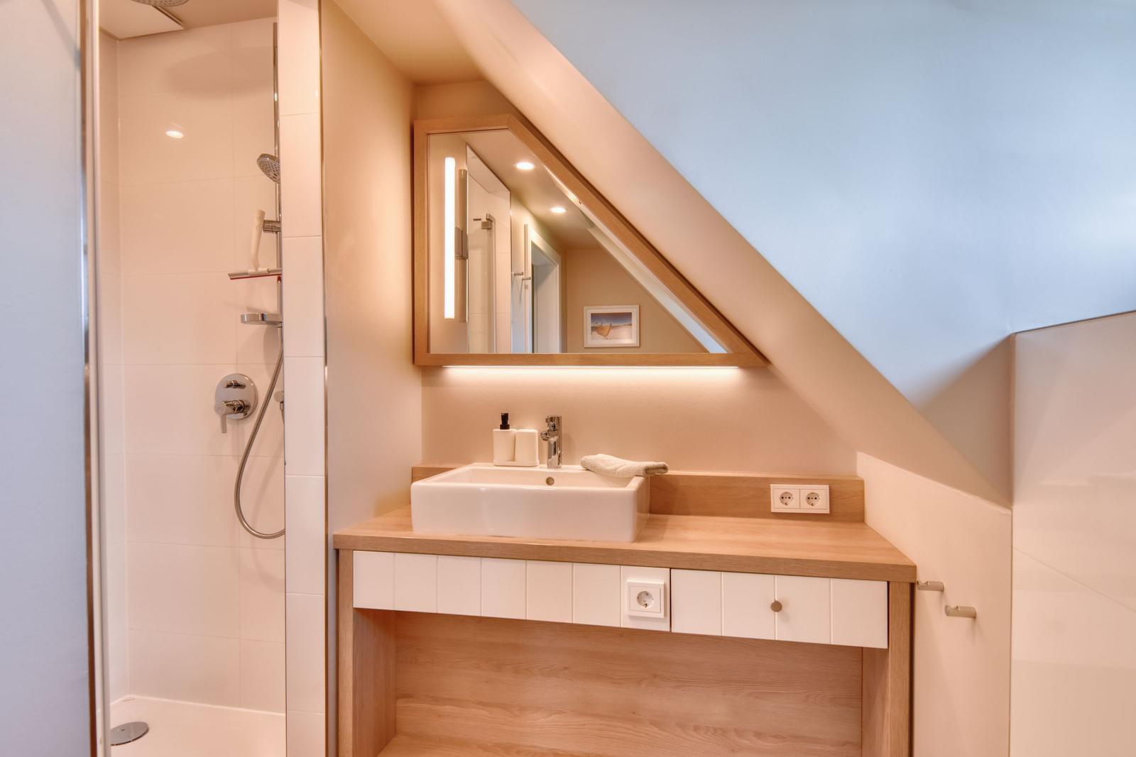 Badezimmer mit Dusche, Waschbecken und Spiegel unter Dachschrägen
