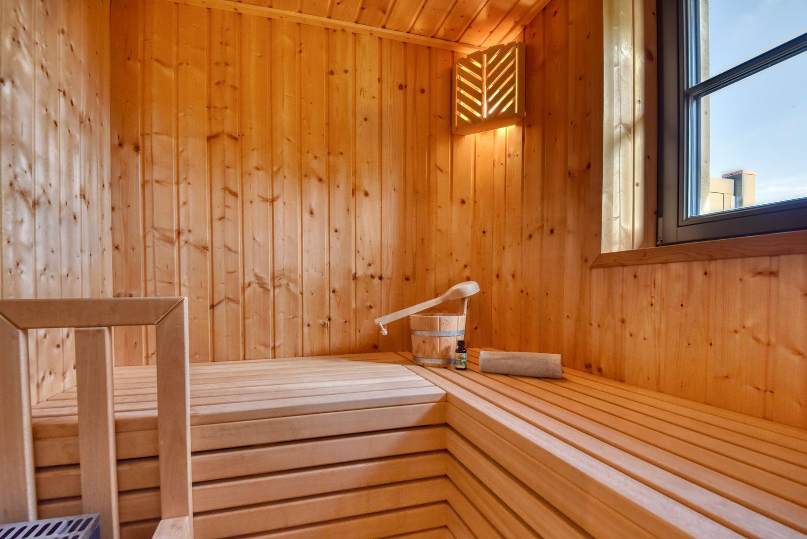 Holzsauna mit Sitzbank, Eimer und Fenster