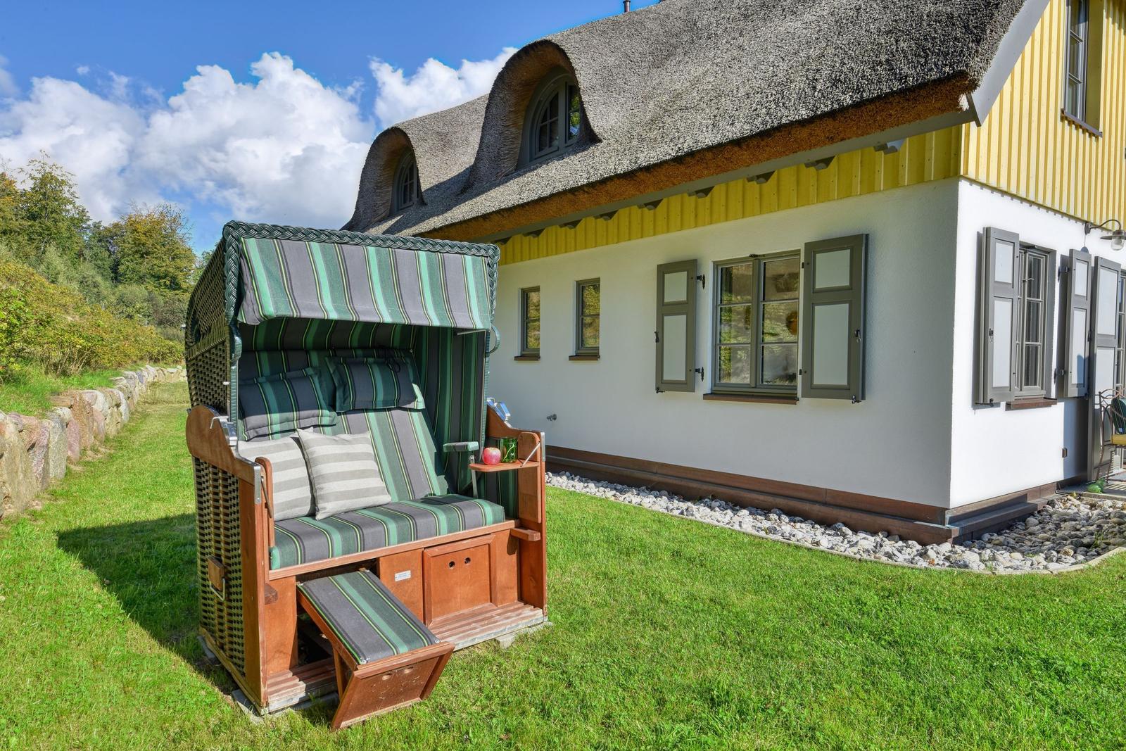 Haus mit Strohdach und Strandkorb im Garten